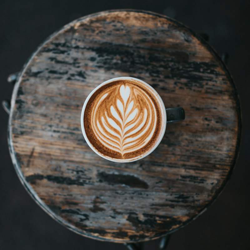 Latte art u šolji na tamnom drvetu