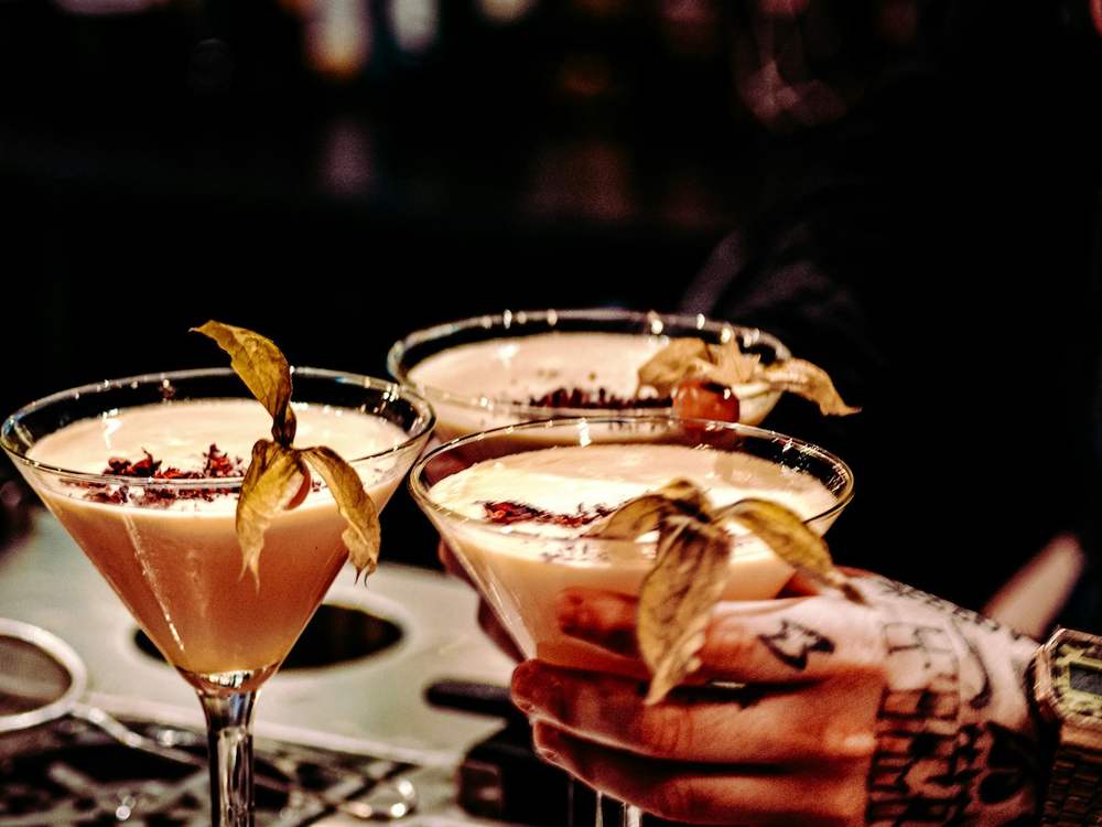Barmen servira tri kremasta koktela ukrašena physalisom